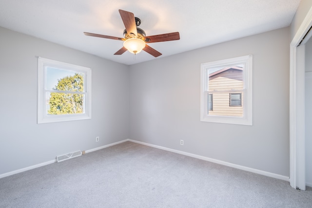 spare room with ceiling fan, light colored carpet, visible vents, and baseboards