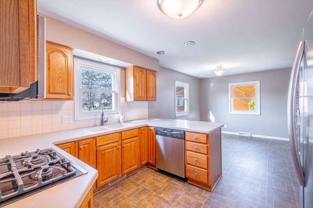 kitchen with a sink, stainless steel appliances, a peninsula, light countertops, and decorative backsplash