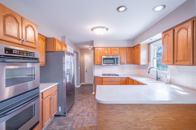 kitchen with decorative backsplash, appliances with stainless steel finishes, light countertops, and a sink