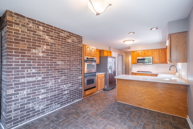 kitchen featuring a sink, appliances with stainless steel finishes, a peninsula, and light countertops