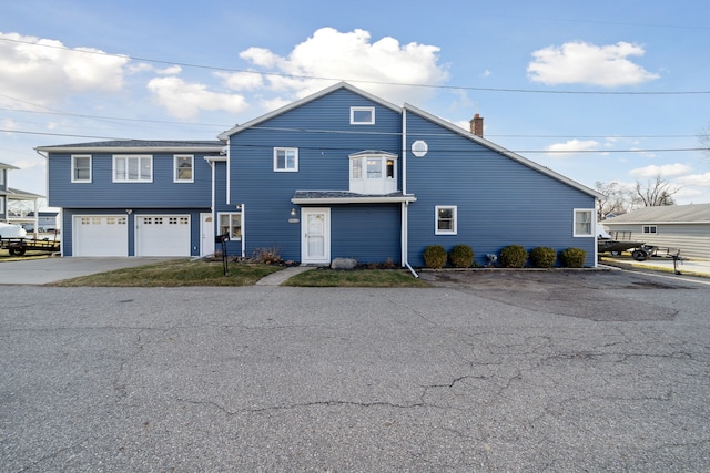 view of front facade featuring a garage, a chimney, and driveway