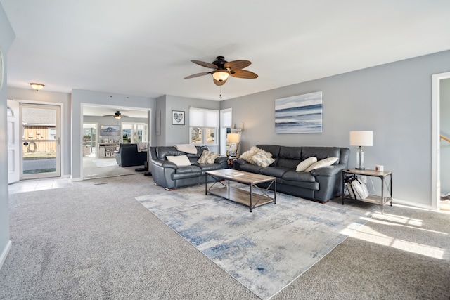 carpeted living area with a ceiling fan and baseboards