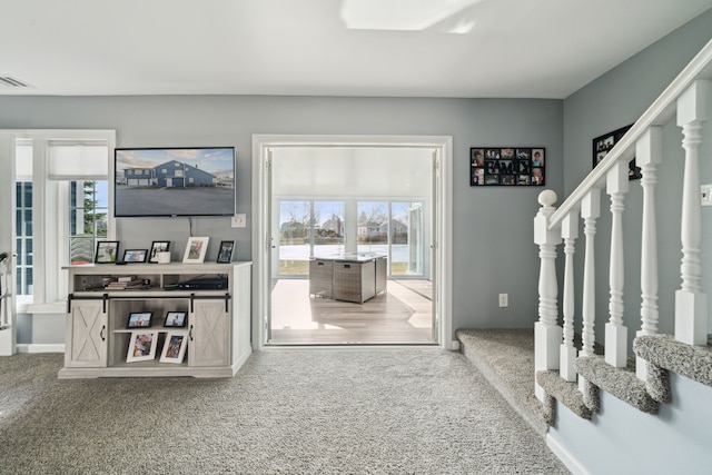 interior space with stairs, plenty of natural light, visible vents, and carpet floors