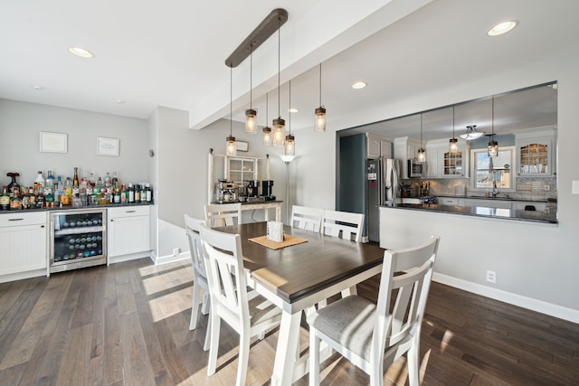 dining space with recessed lighting, wine cooler, a bar, and dark wood finished floors