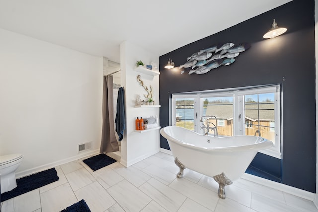 bathroom featuring a shower with shower curtain, baseboards, visible vents, a freestanding bath, and toilet