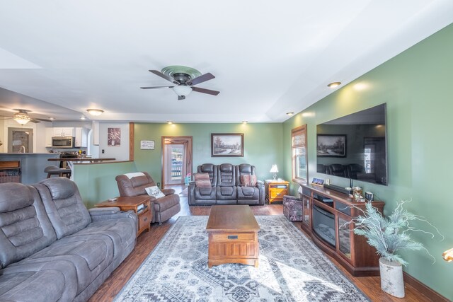 living area featuring a ceiling fan, wood finished floors, and baseboards