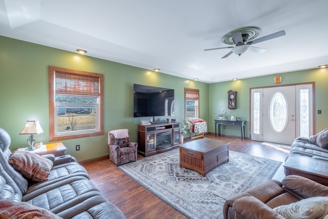 living area with baseboards, ceiling fan, and wood finished floors