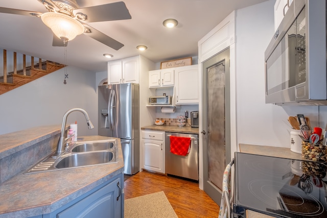 kitchen with light wood-type flooring, a sink, stainless steel appliances, white cabinets, and decorative backsplash