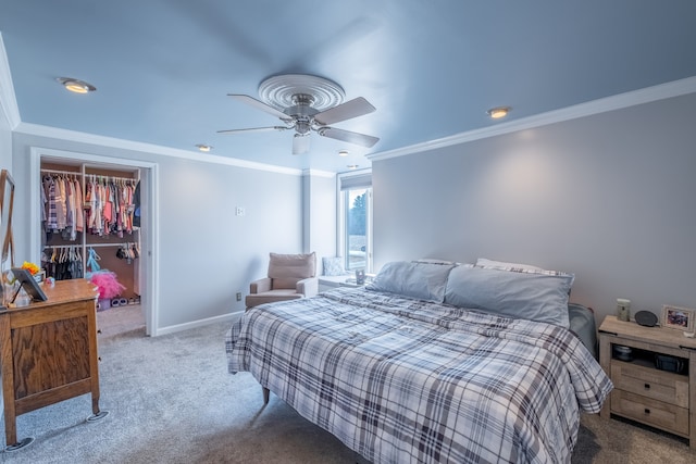 carpeted bedroom with a ceiling fan, baseboards, ornamental molding, a closet, and a walk in closet