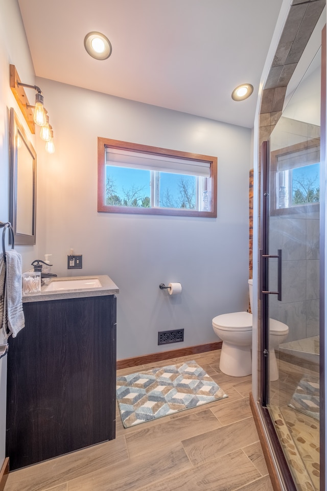 bathroom with toilet, recessed lighting, vanity, a shower stall, and wood tiled floor