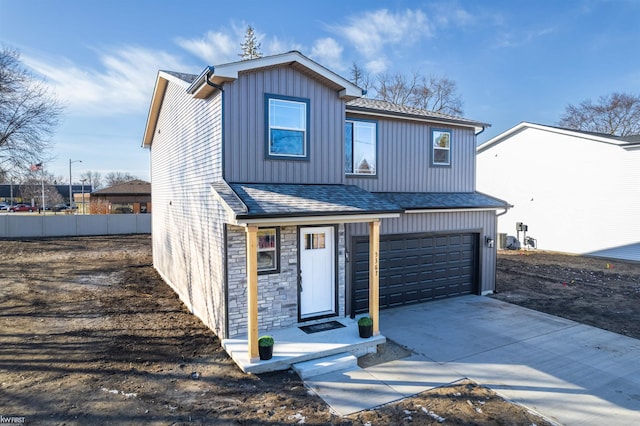 traditional home featuring stone siding, fence, concrete driveway, a shingled roof, and a garage