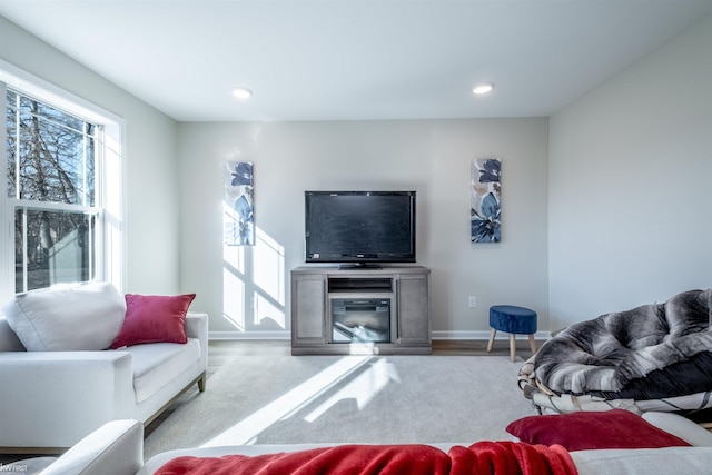 living room with recessed lighting, baseboards, and a glass covered fireplace