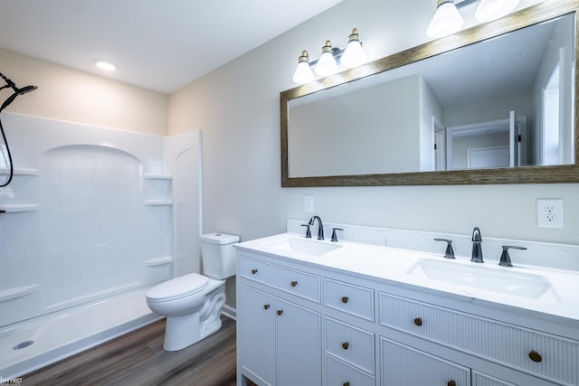 full bathroom with a sink, toilet, walk in shower, and wood finished floors