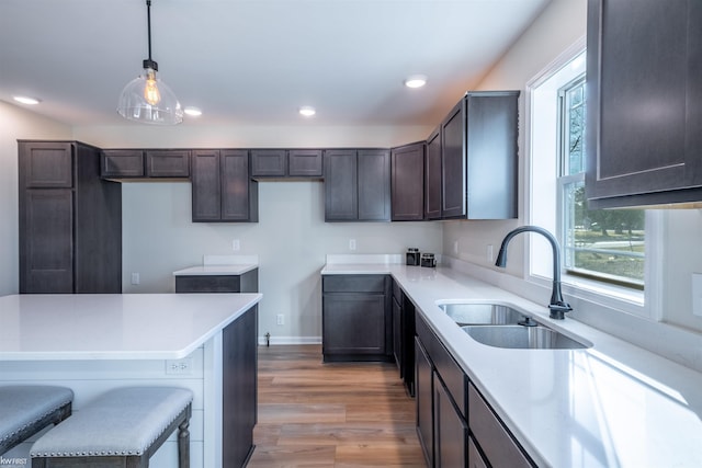 kitchen featuring a sink, dark brown cabinets, recessed lighting, and light wood finished floors