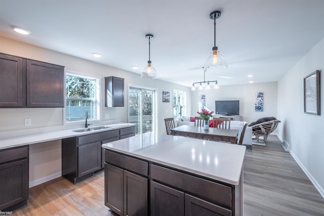 kitchen with a sink, baseboards, light wood finished floors, and light countertops