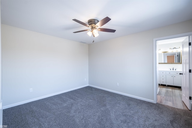 spare room featuring ceiling fan, carpet, baseboards, and a sink