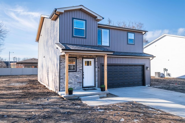 traditional home featuring fence, roof with shingles, a garage, stone siding, and driveway