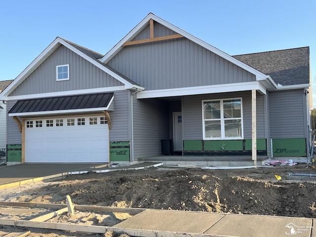 view of front of house featuring an attached garage, metal roof, a standing seam roof, and a shingled roof