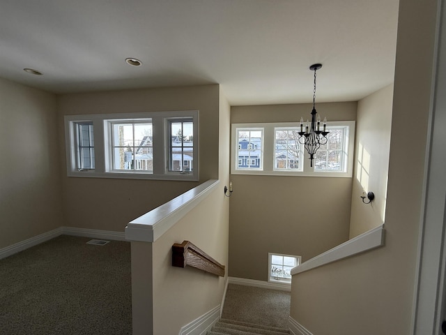 stairway featuring a notable chandelier, visible vents, baseboards, and a wealth of natural light