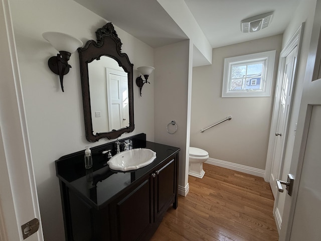 bathroom with visible vents, baseboards, toilet, wood finished floors, and vanity