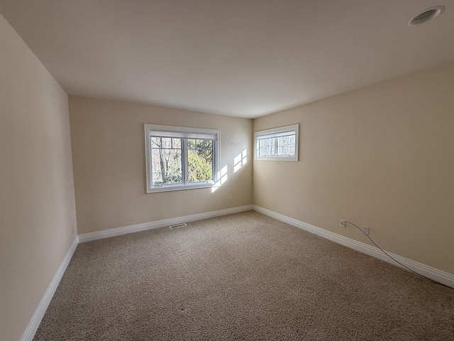 empty room featuring light carpet, visible vents, and baseboards