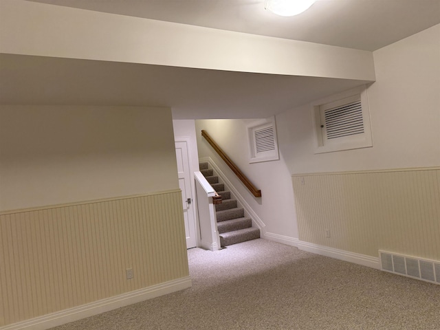 finished below grade area with a wainscoted wall, stairs, carpet, and visible vents