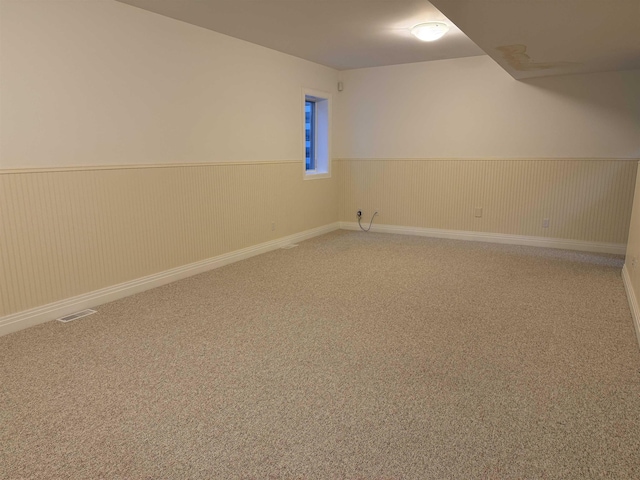 carpeted empty room with visible vents and wainscoting