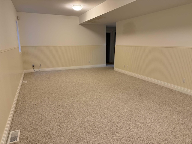 finished basement with carpet flooring, visible vents, and wainscoting