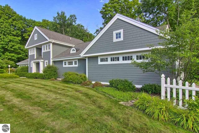 rear view of house featuring a lawn, a shingled roof, and fence