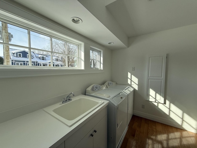 clothes washing area featuring dark wood-type flooring, independent washer and dryer, a sink, cabinet space, and baseboards