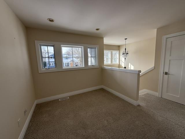 empty room featuring visible vents, baseboards, an inviting chandelier, and carpet flooring