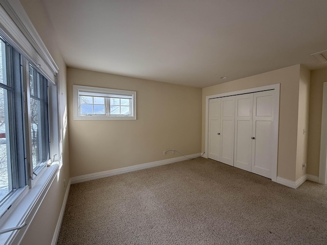 unfurnished bedroom with baseboards, carpet floors, and a closet