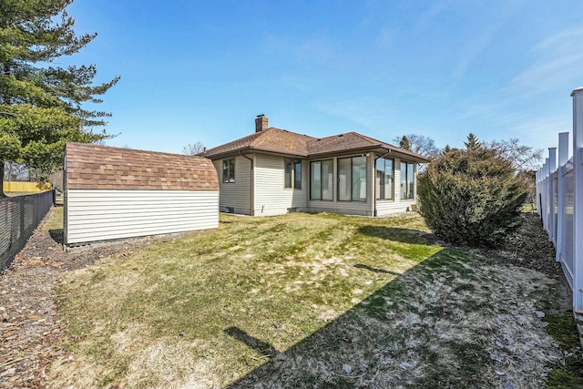 rear view of property featuring an outbuilding, a fenced backyard, a yard, a storage shed, and a shingled roof