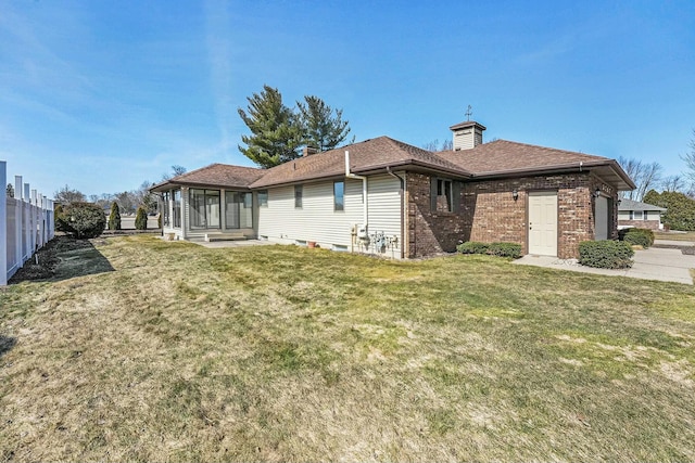 back of property with brick siding, a lawn, roof with shingles, and fence