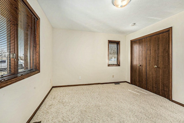 unfurnished bedroom with visible vents, a textured ceiling, a closet, carpet floors, and baseboards