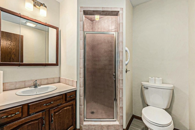 full bathroom featuring vanity, a shower stall, and toilet