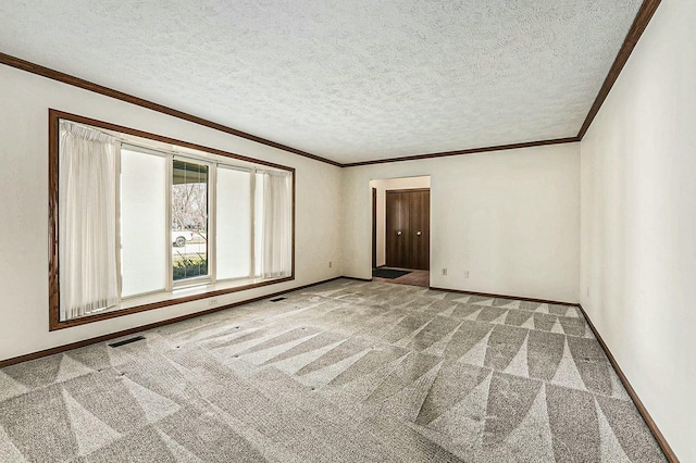 spare room featuring baseboards, carpet floors, a textured ceiling, and crown molding