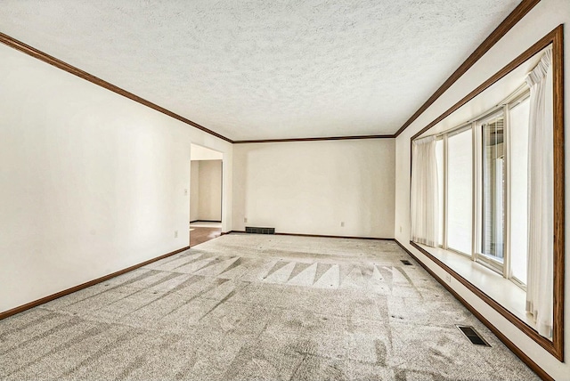 empty room featuring visible vents, ornamental molding, a textured ceiling, carpet flooring, and baseboards