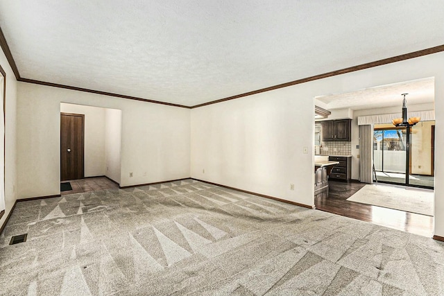 spare room with visible vents, baseboards, an inviting chandelier, a textured ceiling, and dark colored carpet