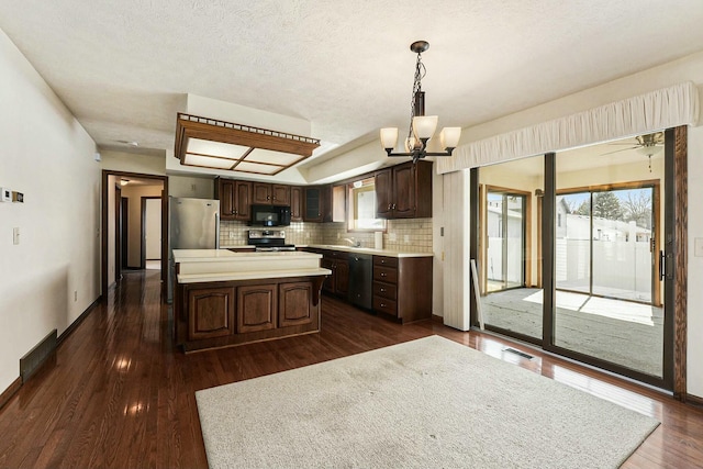 kitchen featuring stainless steel appliances, light countertops, dark brown cabinets, tasteful backsplash, and a center island