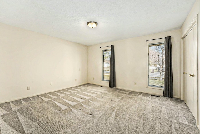 unfurnished bedroom featuring carpet flooring, visible vents, baseboards, and a textured ceiling