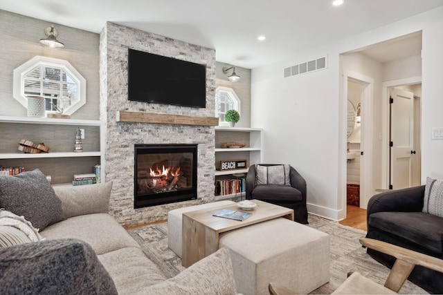 living room featuring wood finished floors, visible vents, baseboards, a fireplace, and recessed lighting