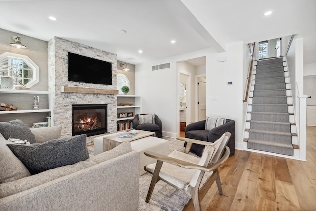 living room with visible vents, plenty of natural light, wood finished floors, and a fireplace