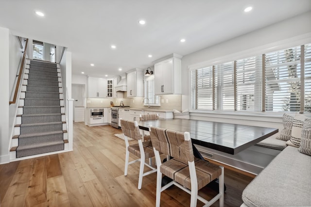 dining space with light wood finished floors, recessed lighting, and stairs