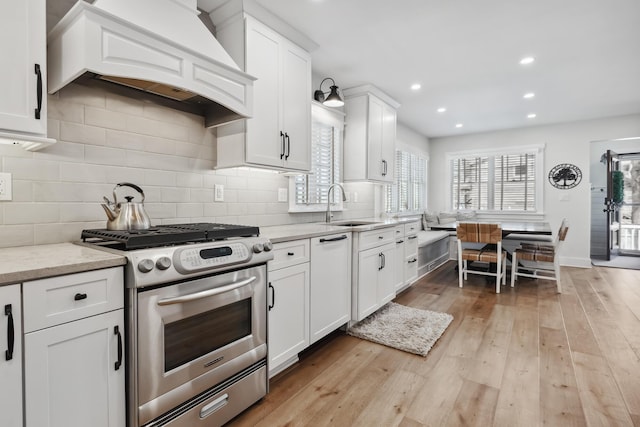 kitchen with tasteful backsplash, custom range hood, white dishwasher, gas stove, and a sink