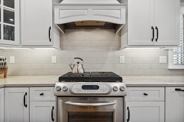 kitchen with white cabinetry, gas range, and premium range hood