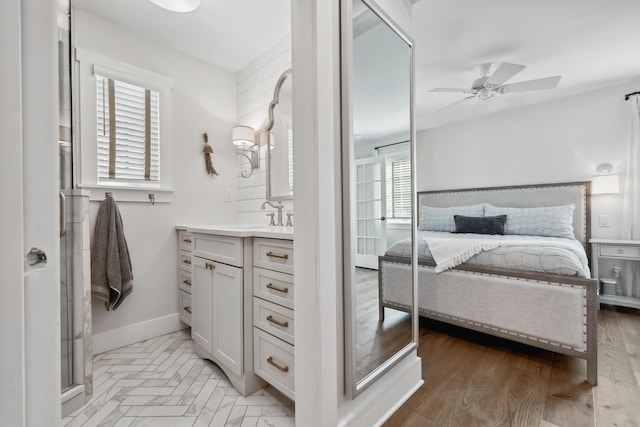 ensuite bathroom featuring vanity, wood finished floors, a ceiling fan, baseboards, and ensuite bathroom