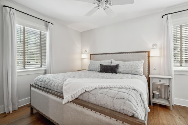 bedroom with multiple windows, wood finished floors, and baseboards