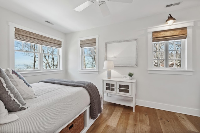 bedroom with visible vents, baseboards, wood finished floors, and a ceiling fan