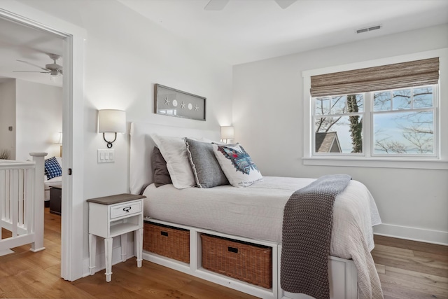 bedroom featuring visible vents, ceiling fan, baseboards, and wood finished floors